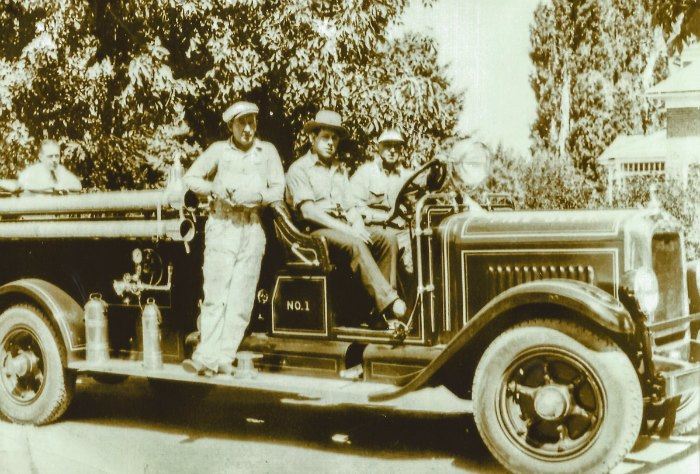 Black and white photo of men on fire truck